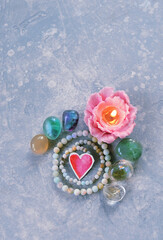 flower candle, crystals, mineral beads, decor heart, on blue-grey background. Magic, esoteric spiritual practice for life balance, soul relax, harmony, love. witchcraft, mystery ritual with gemstones