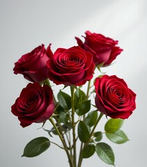 Fototapeta premium Elegant bouquet of vibrant red roses with fresh green leaves isolated on white background