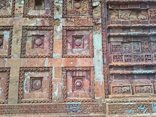 Ancient Terracotta Temple Wall with Sculptures. old terracotta temple wall featuring floral motifs and intricate relief carvings of deities, animals, and patterns