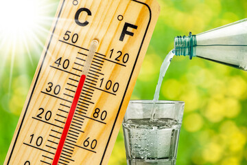 Ein Thermometer zeigt auf seiner Skala große Hitze bis 40 Grad und symbolisch die Aufforderung zum Wasser trinken- FOTOMONTAGE