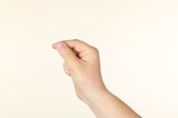 Man holding something in hand on beige background, closeup