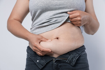 Woman with excessive belly fat on light background, closeup. Overweight problem