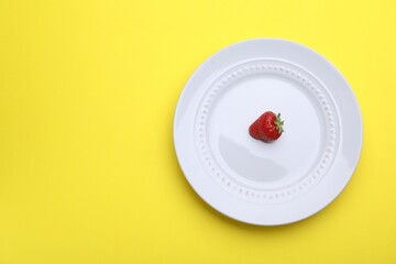 Plate with fresh strawberry on yellow background, top view. Space for text
