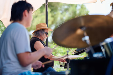 Rock band performing at outdoor venue on sunny day with lively atmosphere