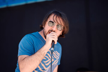 Rock band frontman performs passionately at outdoor festival during summer