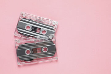 Audio cassettes with magnetic tapes on pink background, flat lay. Space for text