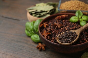 Different aromatic spices on wooden table, closeup. Space for text