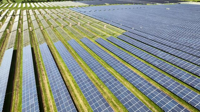 Retreat shot of a ground-mounted solar PV park under construction, with installed panel racks and already mounted solar modules. Construction site of a photovoltaic park. 