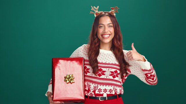 Thumbs up, Christmas gift or face of woman in studio for celebration, giveaway or surprise. Happy, xmas holiday and portrait of person with present box for festive tradition by green background space