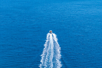 A fast boat sails along the Adriatic Sea leaving a beautiful trail view from drone. Summer...