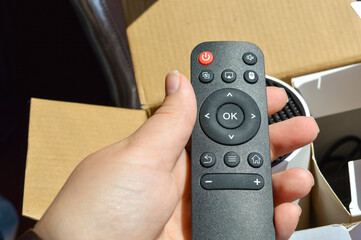 hand holding black remote control with projector box in background — perfect for tech product...