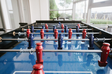 Close-up view of a foosball table with red and blue players, highlighting game details and rods. Great for content about indoor games, leisure, or team activities.