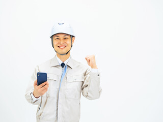 スマホを持ってガッツポーズする作業服を着たミドル男性