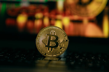 A shiny golden Bitcoin stands upright on a keyboard, symbolizing digital currency, blockchain...