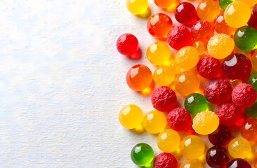 Bright glossy jelly candies in various colors placed on light wooden surface, representing sweet treats and confectionery concept. 
