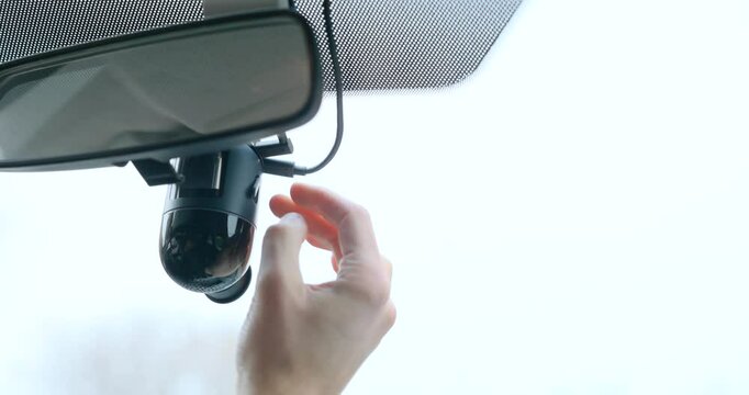 Close-up of hands inserting a SD Card into dashboard camera mounted under a rear-view mirror