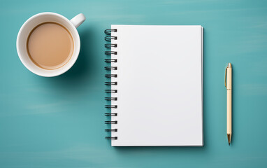Overhead view of coffee notebook and pen on a teal colored background