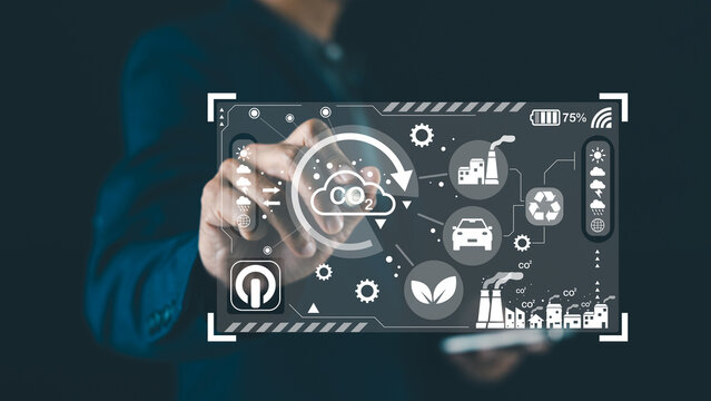 A person interacts with a digital interface displaying icons related to carbon emissions, recycling, eco-friendly energy, and sustainability. - Powered by Adobe