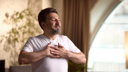 Lifestyle and wellness. Middle aged man practices mindfulness exercises at home in a relaxed,...