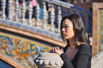 Portrait of a young, beautiful, dark-haired woman in a black long-sleeved T-shirt, pensive and...