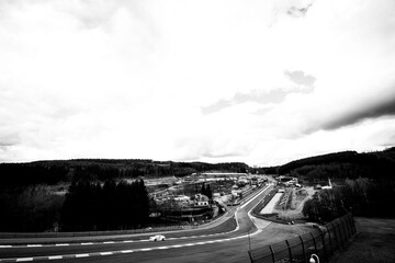 ynamic black and white capture of Spa-Francorchamps race track with a speeding car, sweeping curves...