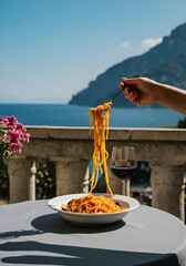 n Italian coastal culinary editorial scene featuring a hand twirling spaghetti above a ceramic bowl, with a glass of red wine nearby. 