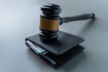 A judge's gavel on a wallet overflowing with US hundred-dollar bills. Wage garnishment, fines,...