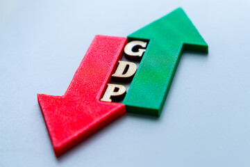 Red arrow and green arrow with wooden block letters spelling "GDP". Fluctuating of Gross Domestic Product, economic volatility, conflicting trend, uncertainty in the financial market.