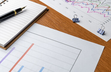 Financial charts and graphs with notebook on table. Business analysis, financial planning, status report, data interpretation concept.