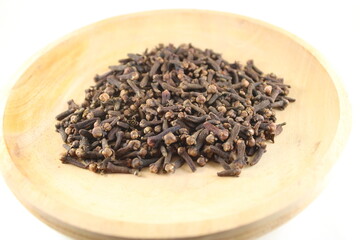 Aromatic dried cloves arranged on a rustic wooden plate. Perfect for culinary, herbal, organic, and traditional spice themes in food and natural health visuals