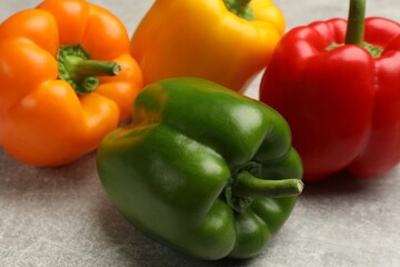 Fresh colorful bell peppers on gray textured table, closeup