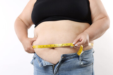 Overweight woman measuring her belly with tape on white background, closeup
