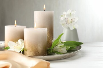 Burning candles and beautiful flowers on white table