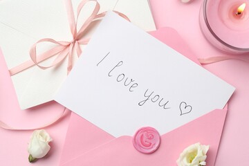 Stack of letters, card with phrase I Love You, burning candle and flowers on pink background, flat...