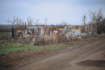 A completely destroyed house stands with only its frame and crumbling walls remaining, situated in...