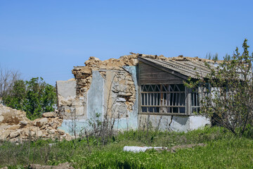 A completely destroyed house stands with only its frame and crumbling walls remaining, situated in...