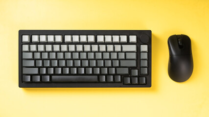 Mechanical keyboard with gradient gray keycaps paired with a black wireless mouse on a bold yellow...
