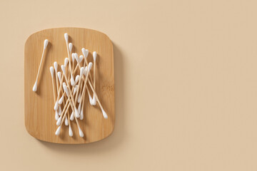 Bamboo ecological cotton swab on wooden stand on beige background. Zero waste, sustainable...