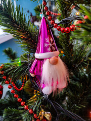 Christmas tree with silver and gold decoration, pink dwarf, red beads and other decorations in the background. New year