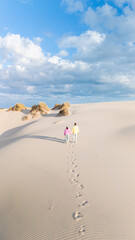 Couple walks hand in hand through the stunning sand dunes of Denmark under a blue sky