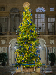 Christmas tree with lights and ornaments in a historic courtyard in Turin, Italy, surrounded by...