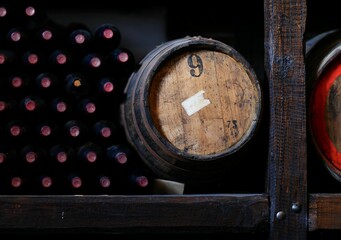 Rustic wine cellar with barrels and bottles.