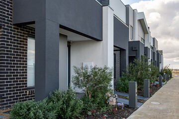Modern townhouse frontages in a newly developed Australian suburb, featuring small front garden,...