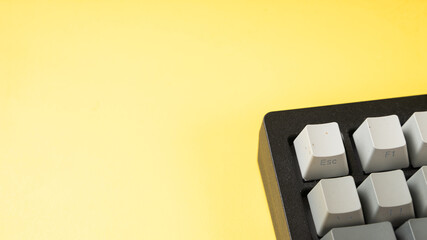 Minimalist mechanical keyboard with gradient gray keycaps placed on a vibrant yellow background,...