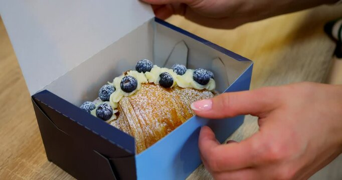 Mindful savoring of berry croissant held in box, hands cradling flaky treat, berry notes repeat flavor focus, mindful eating theme balancing indulgence with wellness for health-conscious content
