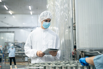 Industrial worker using digital tablet inspecting food process for production quality control in...