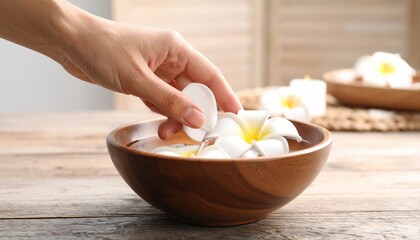Hand Placing White Flower Petal In Wooden Bowl