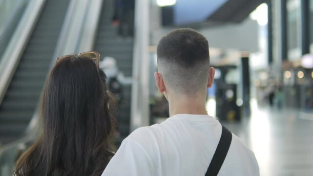 Man and a woman are walking together in an airport. The man has a black backpack on his back