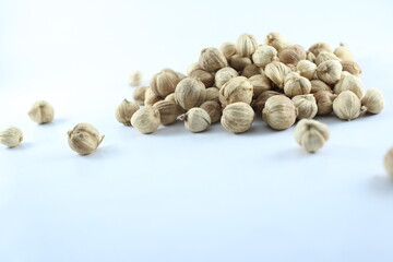 Dried white cardamom pods on a plain white background, with several pods scattered around,...