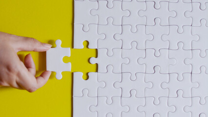 Hand holding the final puzzle piece to complete the business solution, symbolizing teamwork and...